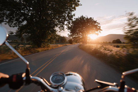 Motorcycle ride along a scenic road at sunset with trees and mountains in the backgroundの素材