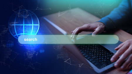 User typing on a laptop with a digital interface displaying a search bar and data visualizationの写真素材