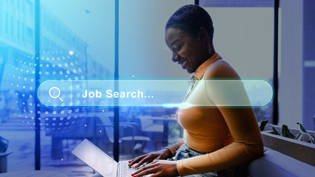 Woman engaging in job search on laptop in a modern workspace during daytimeの写真素材