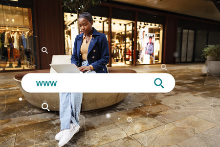 Young woman working on a laptop in a stylish shopping mall during evening hoursの写真素材