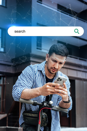 Young man using smartphone while standing on scooter in front of modern building during daytime