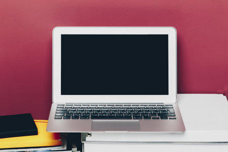Home office of a woman with laptop against dark pink wall