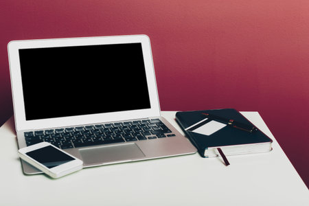 Home office with laptop against dark pink wall