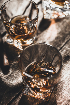 Two whiskey glasses close up on old wooden table