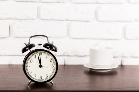 Alarm clock on brown wooden table and coffee cup