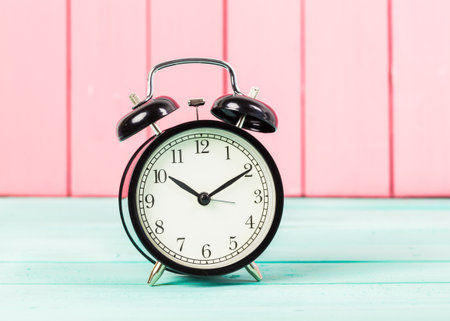 Black vintage alarm clock on wooden table