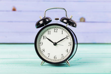 Black vintage alarm clock on wooden table