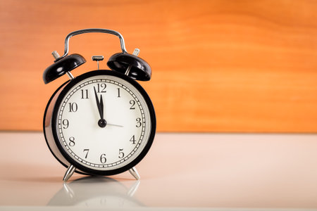 Black alarm clock on the table. Twelve oclock