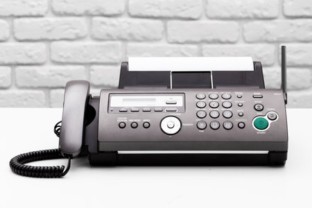 Black office fax machine with paper inside