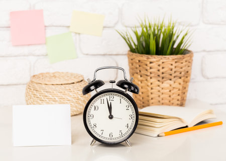 Reminder note and black old-fashioned alarm clock