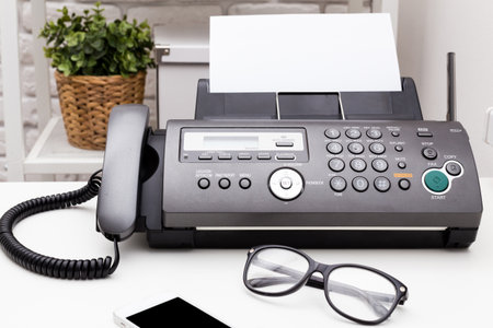 Black office fax machine with paper inside