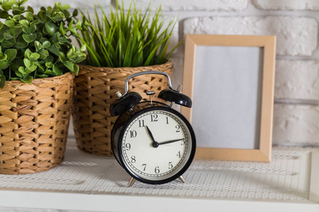 Black alarm clock standing near the bed
