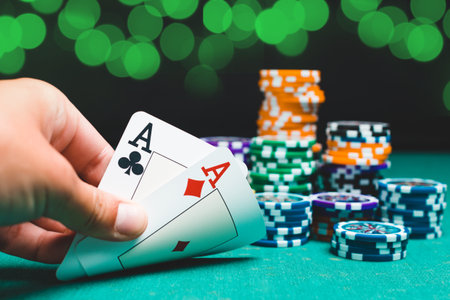 Chips and cards for poker on green table with bokeh