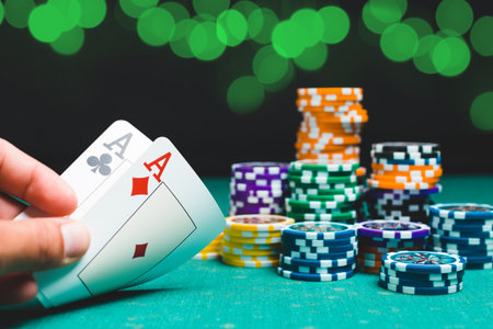 Chips and cards for poker on green table with bokeh