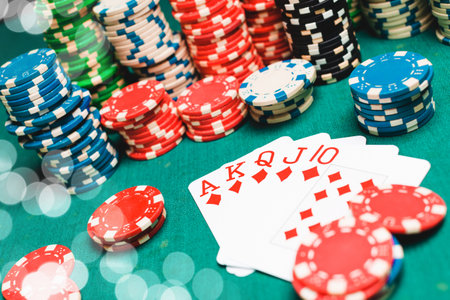 Chips and cards for poker on green table with bokeh