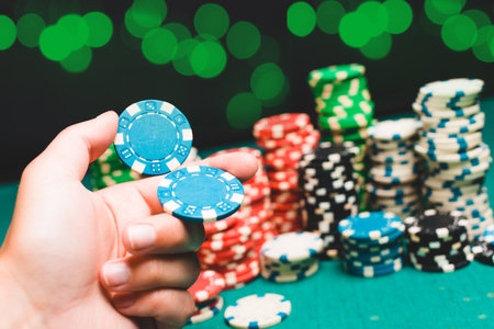 Chips and cards for poker on green table with bokeh