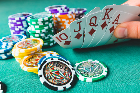Chips and cards for poker on green table with bokeh