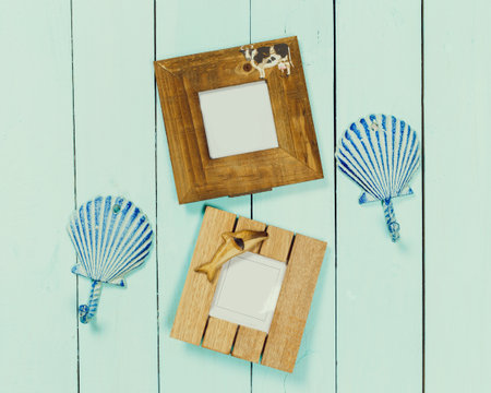 Decoratively designed picture frames and shell shapes arranged on a light blue wooden surface