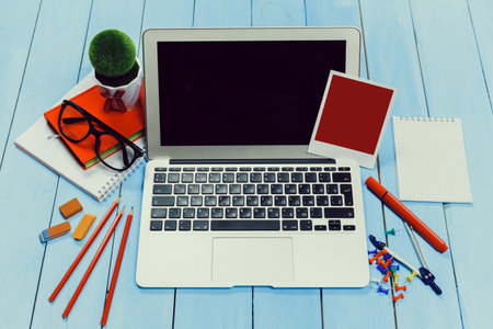 Workspace setup with laptop, stationery, and creative elements on a blue wooden table
