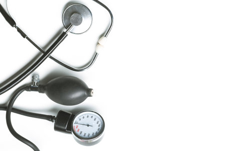 Medical tools including a stethoscope and sphygmomanometer on a plain background