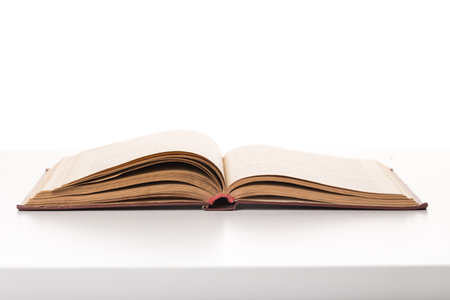 Old leather-bound book displayed on a white surface in a well-lit setting