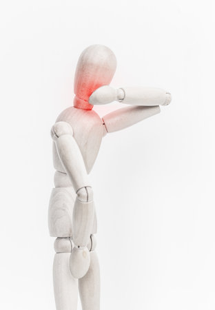 Wooden mannequin depicting discomfort in shoulder area during a creative practice sessionの写真素材