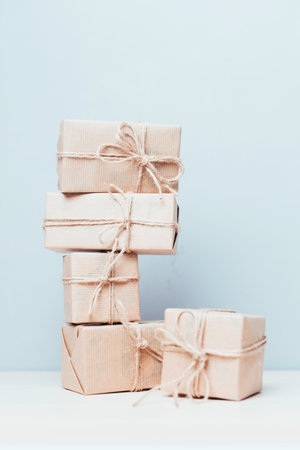 Brown paper wrapped gifts stacked on a table with a soft blue backgroundの写真素材