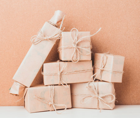 Gift boxes and wrapped presents stacked on a wooden table with a plain background