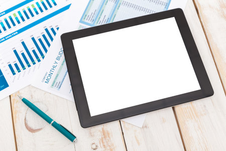 Office workspace with digital tablet and financial documents on wooden table