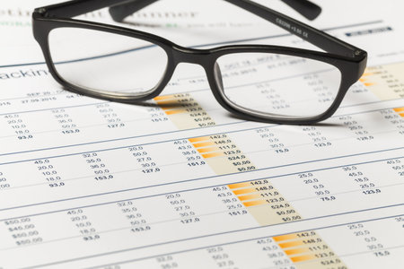 Glasses placed on financial documents full of data and calculations for analysis