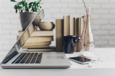Modern workspace with laptop, books, and coffee on a tidy deskの写真素材