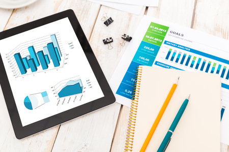 Business analysis report featuring graphs and charts on a digital tablet with stationery