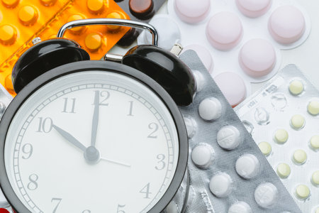 Medication and alarm clock on a surface with various pill packages at midday