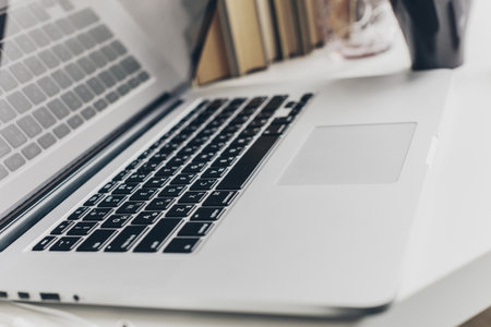 Laptop placed on a desk next to books in a modern workspace during daylight hours