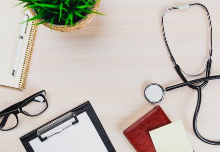 Workspace with stethoscope, notepad, glasses, and plant in a medical office