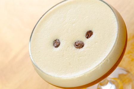 Coffee cocktail topped with coffee beans served in a stylish glass on wood tableの写真素材