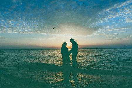 Couple enjoying sunset by the beach, creating a romantic atmosphere near the ocean