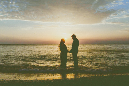 Romantic couple holding hands by the ocean during sunset at a serene beach