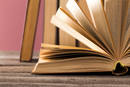 Open book resting on a wooden surface with blurred books in the background