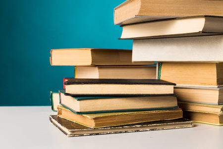 Stacked books on a white table against a turquoise background in a cozy reading space