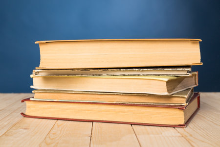 Stacked old books on a wooden table with a blue background in a cozy reading nook