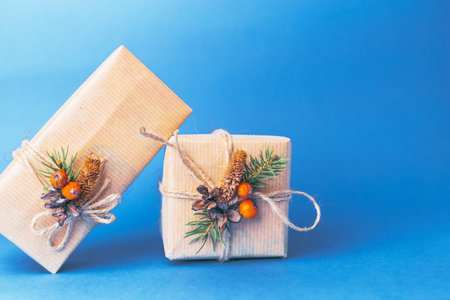 Unique holiday gifts wrapped with rustic decorations on a blue background