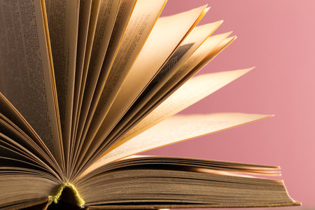 Open book with fanned pages displaying detailed textures against a vibrant background