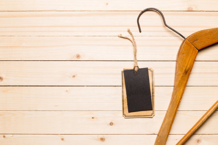 Wooden hanger with blank tag resting on a wooden surface in a simple setupの写真素材