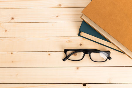 Books and glasses on a wooden table in a cozy study areaの写真素材