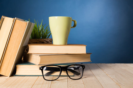 Cozy reading space with books, a cup, and glasses on a wooden tableの写真素材