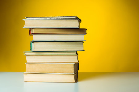 Stacked books on a table with a vibrant yellow background in a cozy setting