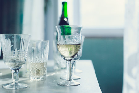 Elegant table setting with crystal glasses and a green bottle during a cozy gatheringの写真素材