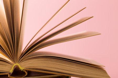 Open book with turning pages on a pink background showcasing the beauty of readingの写真素材