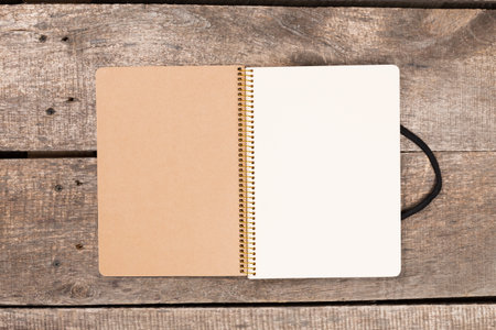 Notebook open on wooden surface with blank pages ready for writing or drawing ideas